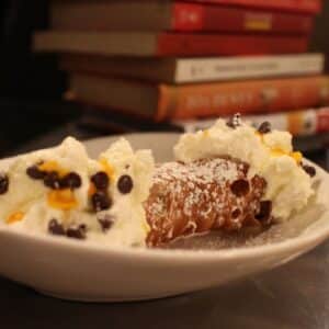 cannoli sitting on plate in front of stack of books