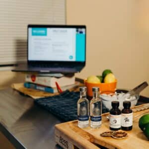 computer set up with cocktail ingredients on table