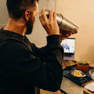 man shaking cocktail during virtual happy hour event