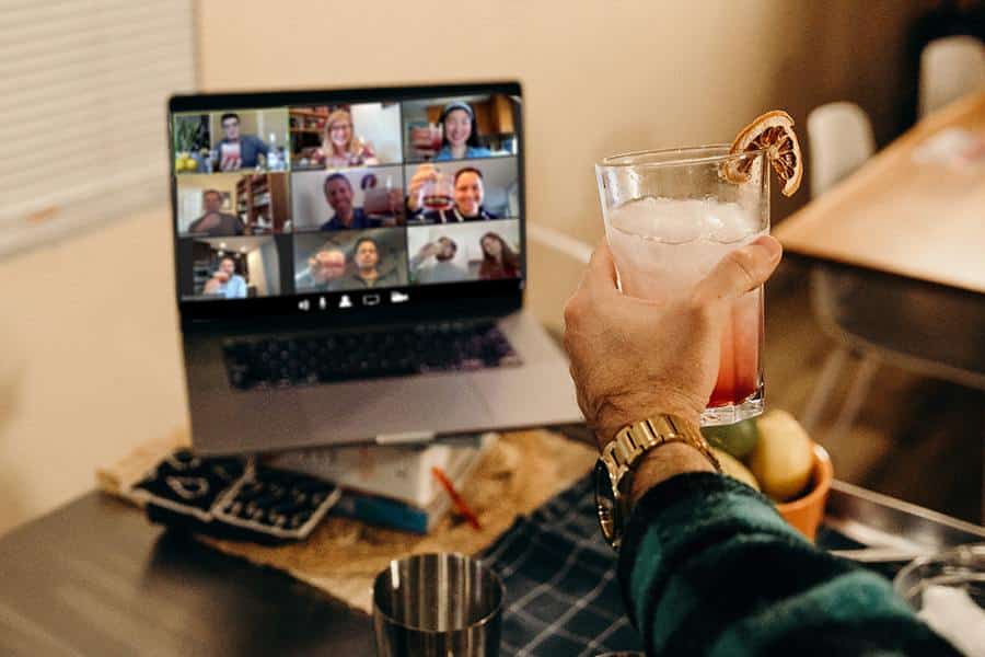 virtual happy hour computer screen with hand holding cocktail up to screen