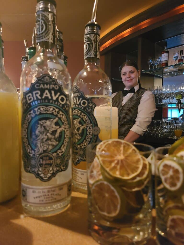 Bartender at El Gaucho in Bellevue Seattle Smiling with tequila bottles
