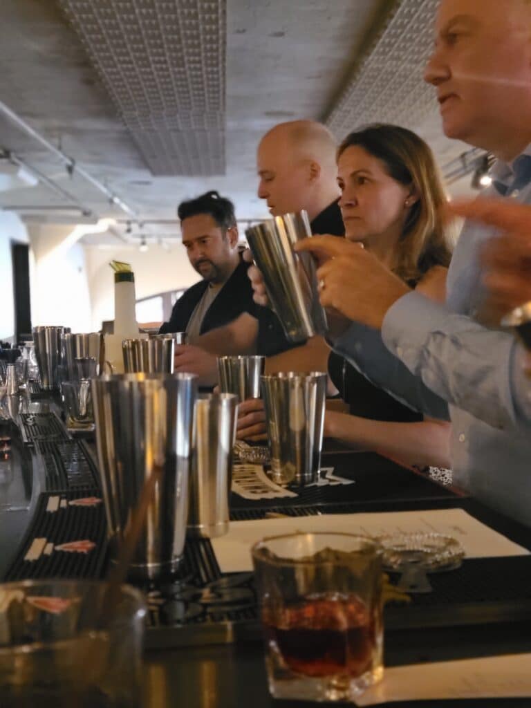 Group making cocktails with man holding shaker at Wild Ginger Bar during seattle dining experiences