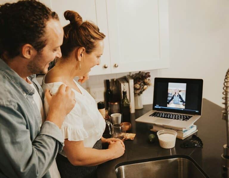 couple smiling at computer screen during virtual client entertainment event