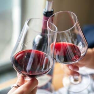 red wine toasting two glasses together with hands holding them