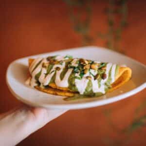 Hand holding a plate with a sweet potato quesadilla with cashew crema in the San Francisco Mission District restaurant