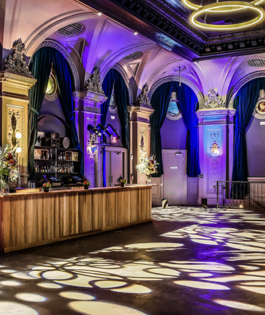 The events space at August hall has high windoes, swirling lights, and a big wood bar