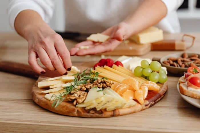 hands building a charcuterie board - one of Avital Experiences' last minute holiday party ideas for work