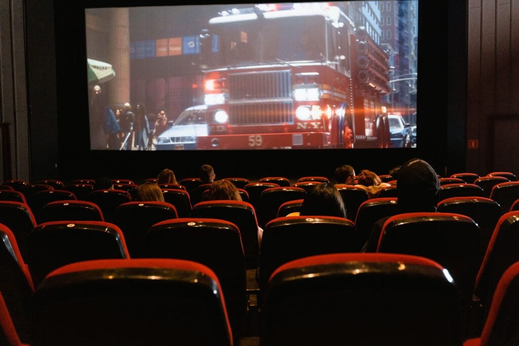 Movie theater with fire truck on screen and people watching