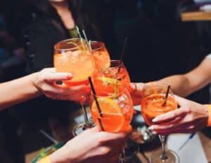 hands toasting aperol spritz cocktails during north beach food tour