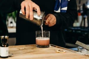 pouring pink cocktail into glass