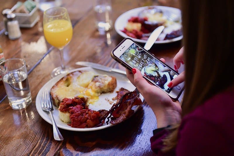 woman taking photo during williamsburg tour, on of the best nyc food tours