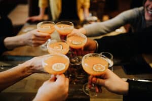 group toasting with orange cocktail glasses with hands
