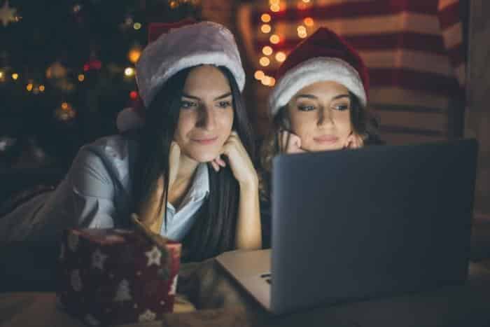 two women wearing santa hats and playing holiday trivia