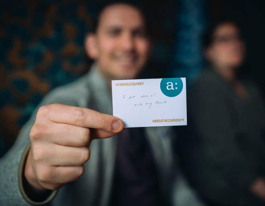 man holding up embrace quirky card during corporate entertainment