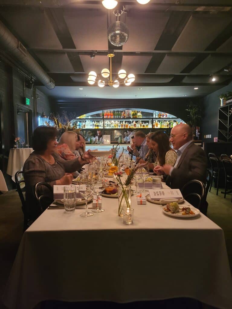 Group of Guests sitting at Long Table Eating during a Dallas Interactive Private Dining Meal