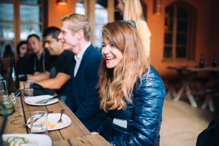 group sitting at table and smiling during food tour