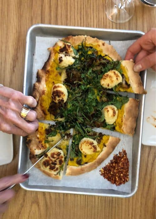 hands taking piece of nyc east village tour’s vegan pizza