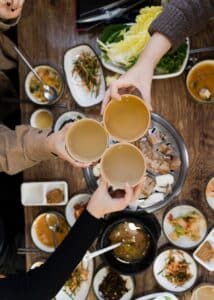 hands toasting drinks over table of korean bbq during koreatown food tour in los angeles