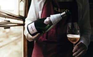 hand serving glass of krug rose champagne