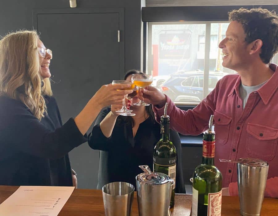 three people toasting cocktails at bar during client entertainment event
