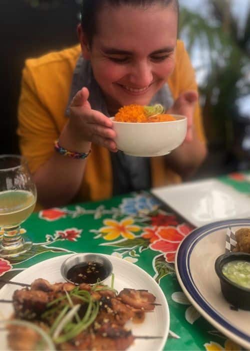 woman holding bowl of food and smiling during mission food tour