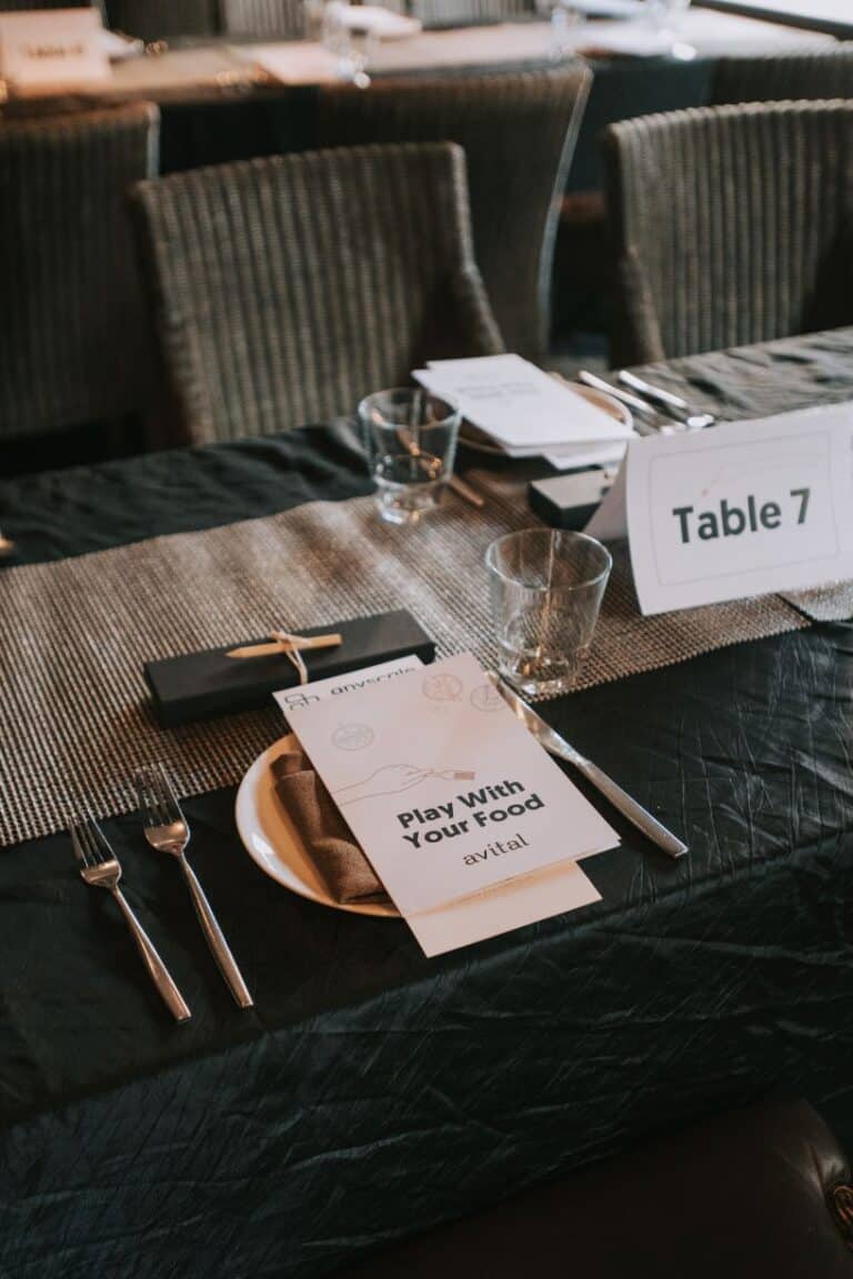 A detailed place setting at a dining table with a booklet titled 'Play With Your Food,' highlighting the unique offerings of restaurants with private rooms NYC for private and interactive meals