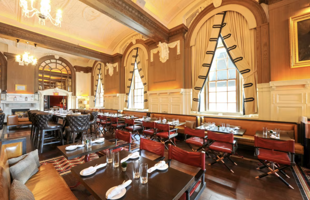 The oak Long bar and kitchen is lush with red furniture and cream colored curtains