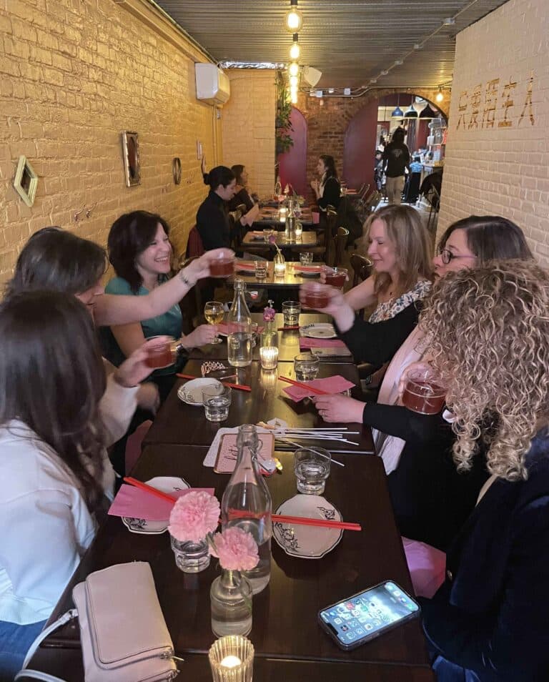 group of women toasting cocktails during east village food tour in nyc