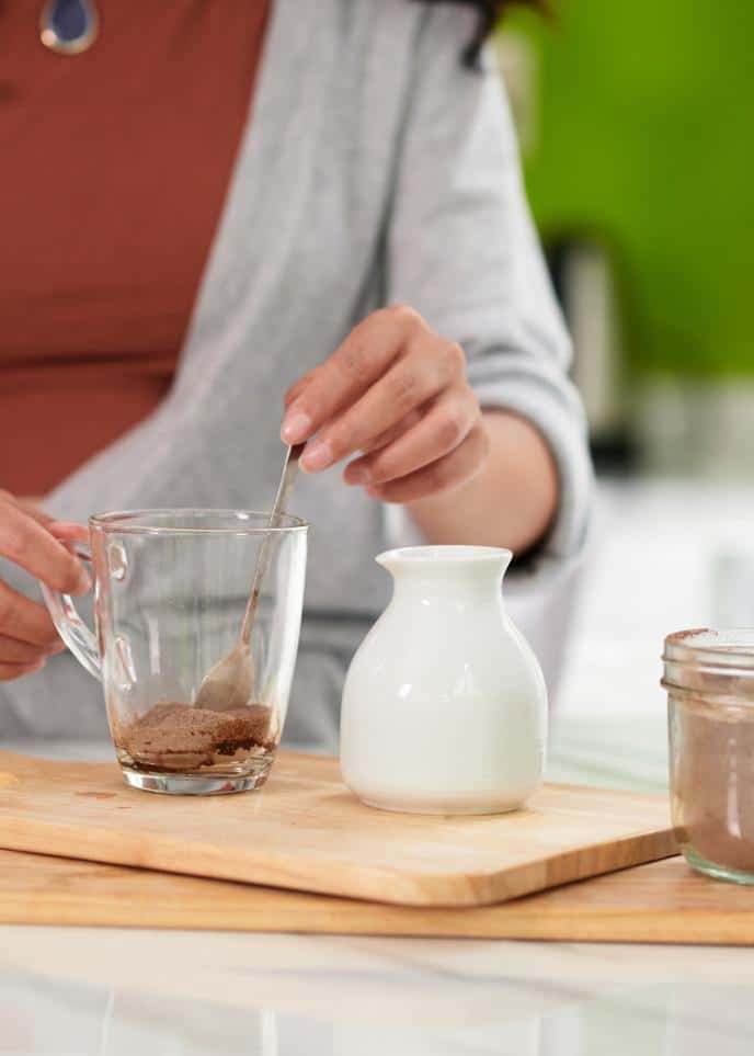 woman adding coco to mug for hot chocolate party