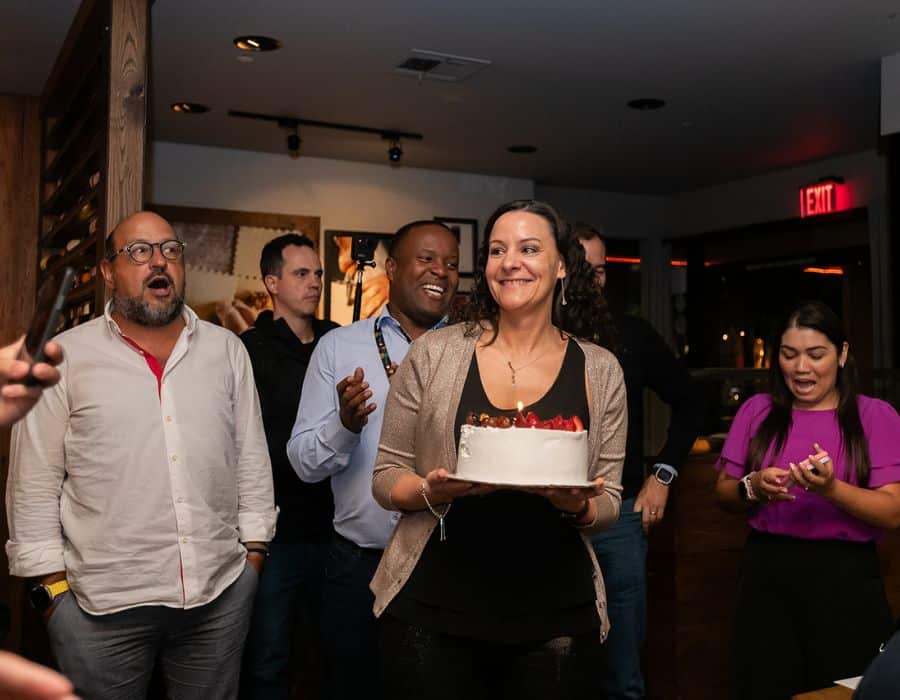 woman holding cake during nyc birthday dinner large group