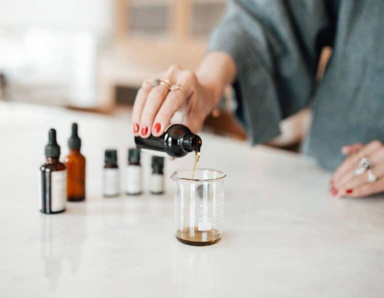 hand pouring bitters into glass jar during bitters blending bar