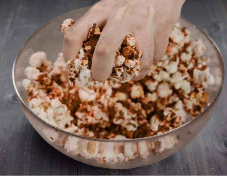hand grabbing seasoned popcorn during popcorn seasoning bar