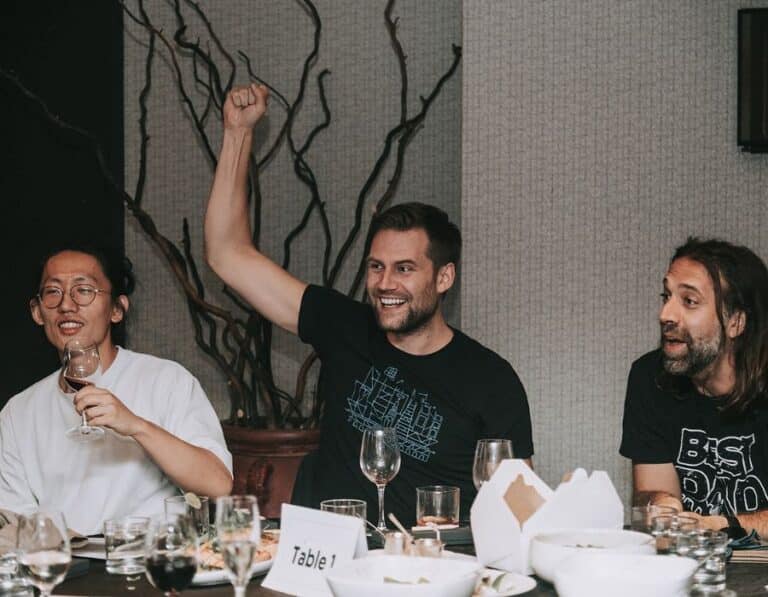group of men sitting at table and cheering during interactive meal trivia