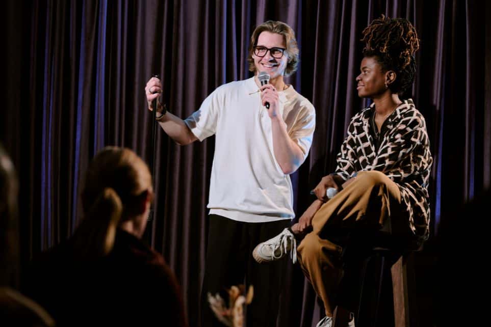 man and woman on stage during comedy performance in nyc