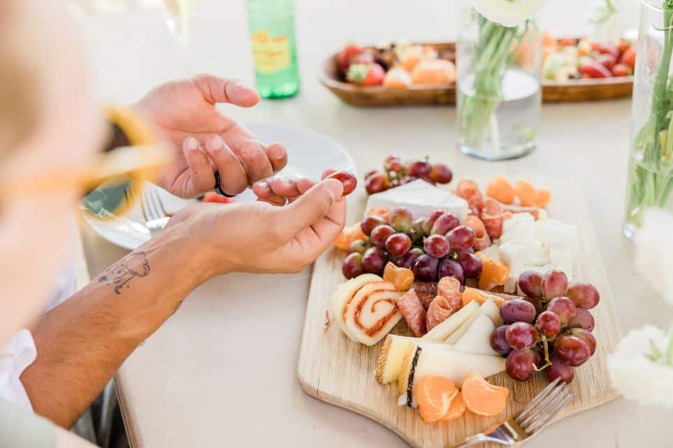 hand placing grapes on charcuterie board