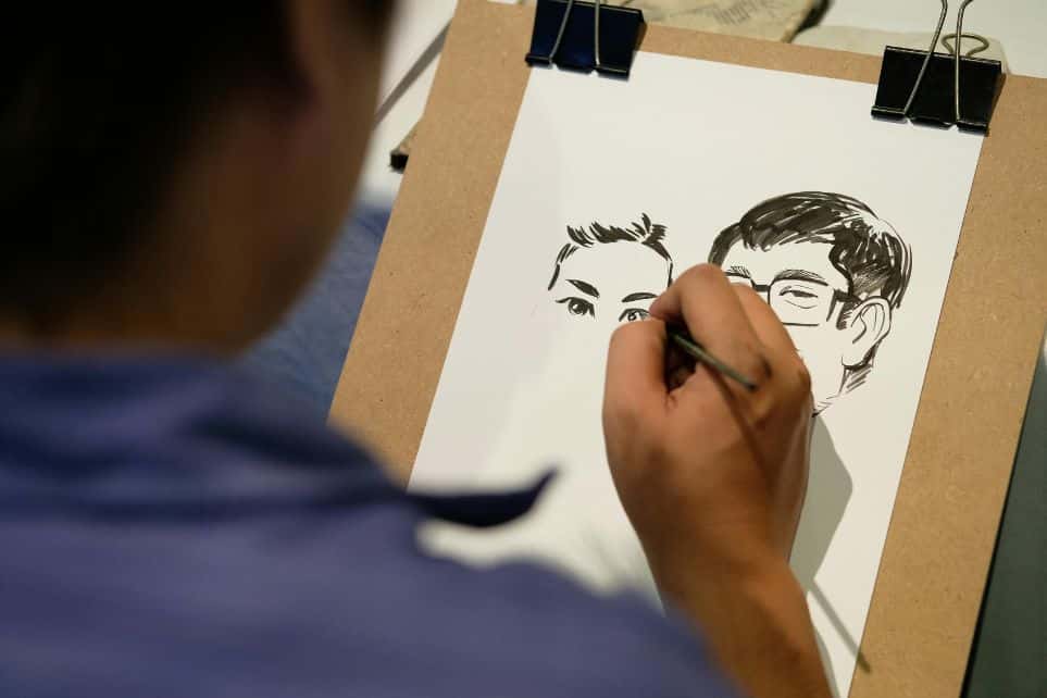 man painting cartoon portraits during corporate event