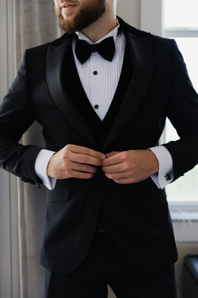 a man buttons up his suit jacket over a nice shirt and tie