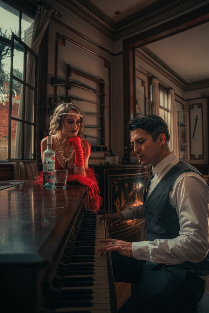 a flapper watches a well-dressed man play the piano