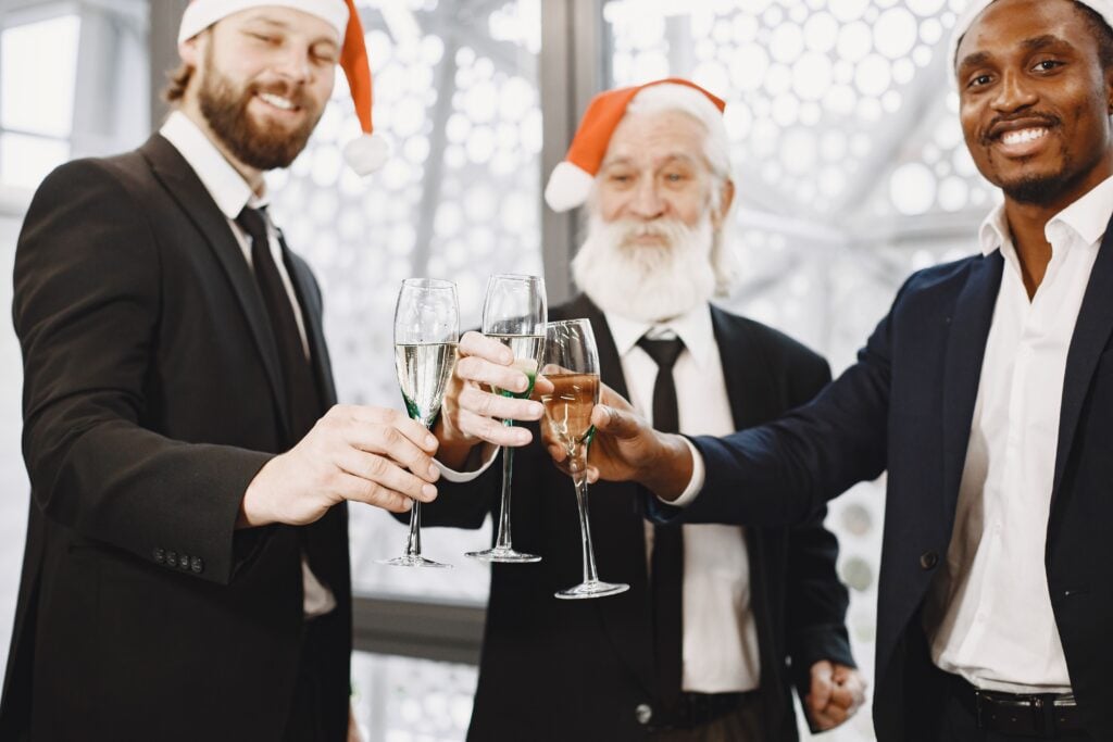 Three men in santa hats cheers
