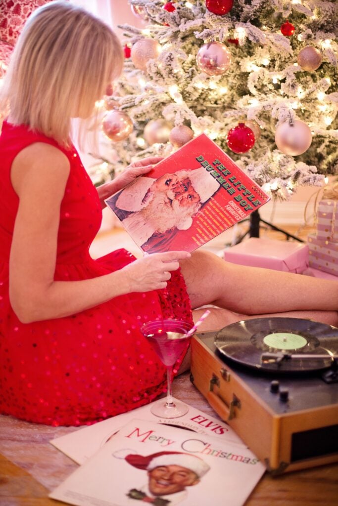 A woman admires a Christmas record as she sits beneath the tree