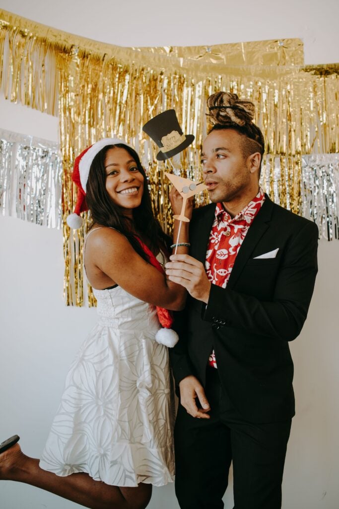 Twp friends pose in front of tinsel with holiday clothes on