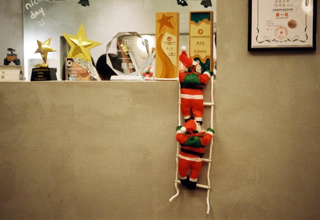 Santas sneak up to an office award on a shelf