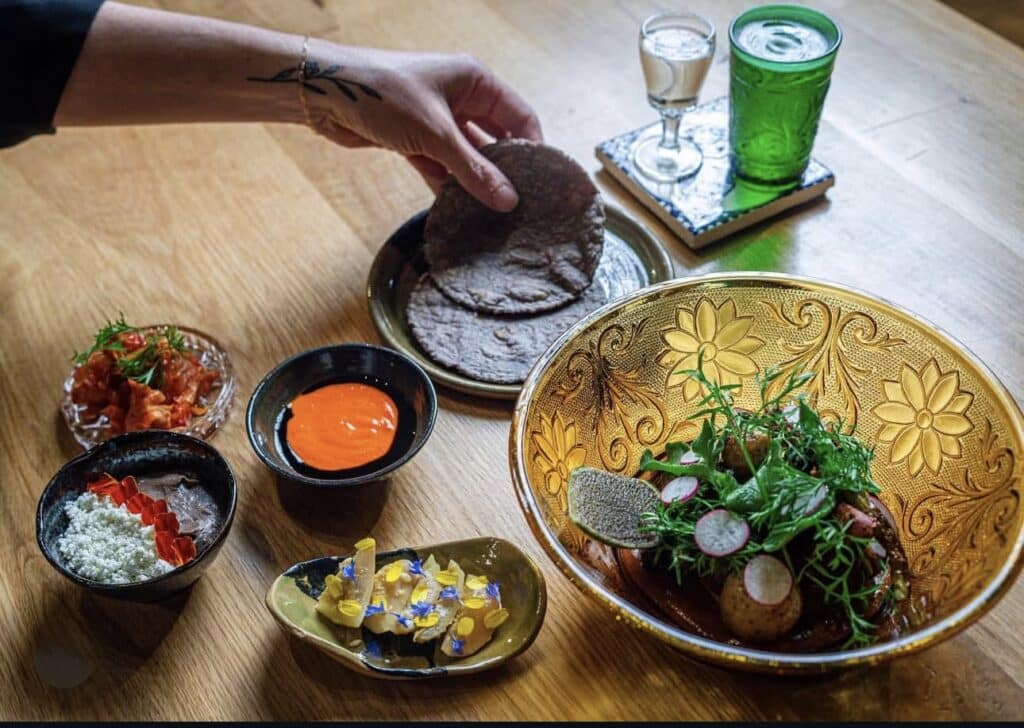 hand reaching at table of food at bruto in denver