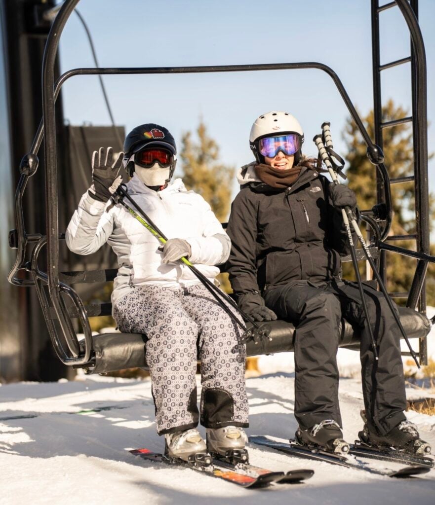Team members ride the ski lift to the top of the mountain with glee