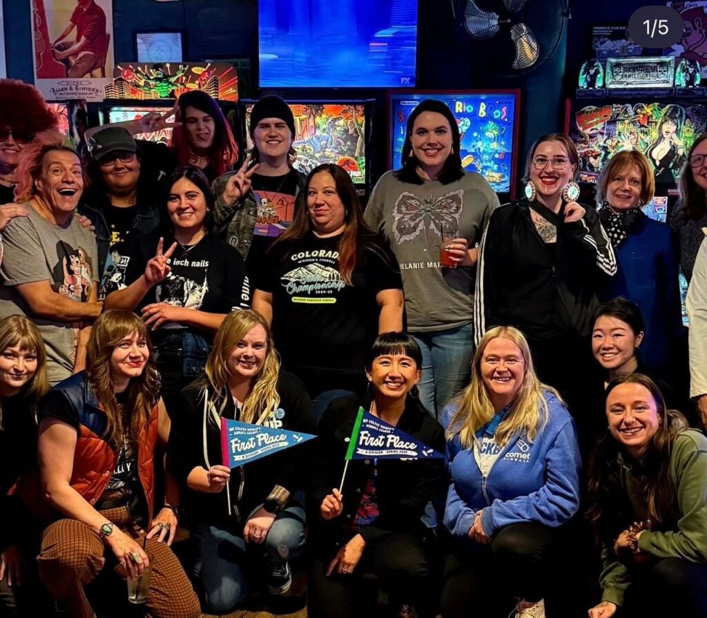 Coworkers pose in front of the arcade games at 1Up arcade bar in Denver