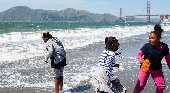 A family plays in the waves at Baker Beach