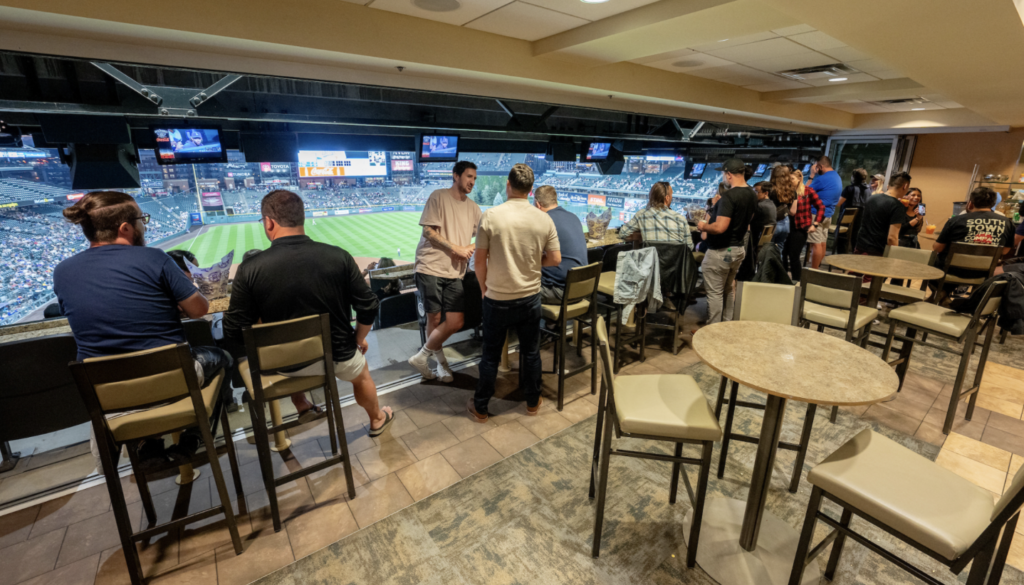 Team members enjoy the view from a suite at the Rockies Stadium in Denver