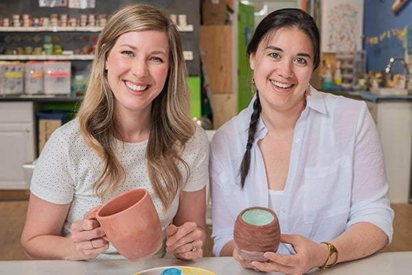 Two coworkers show off their creations after s class at Ceramics in the City