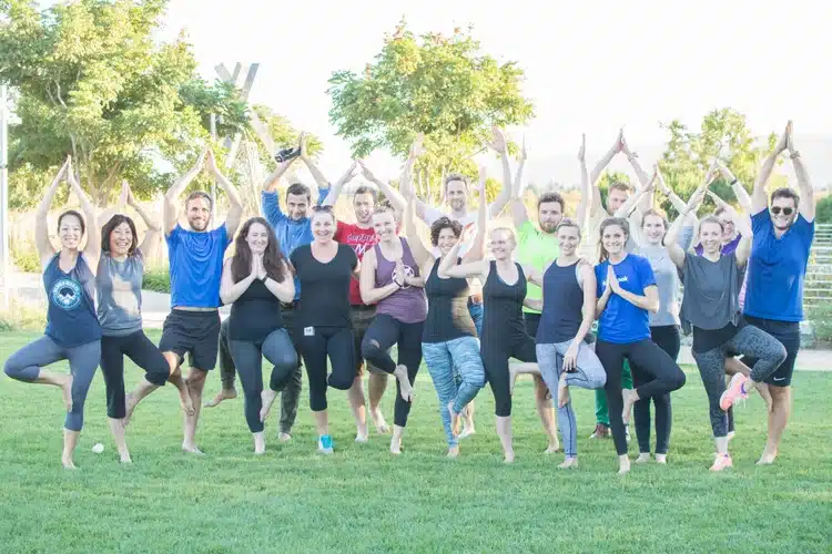 A corporate tea, stands in tree pose for a photo at a team building event