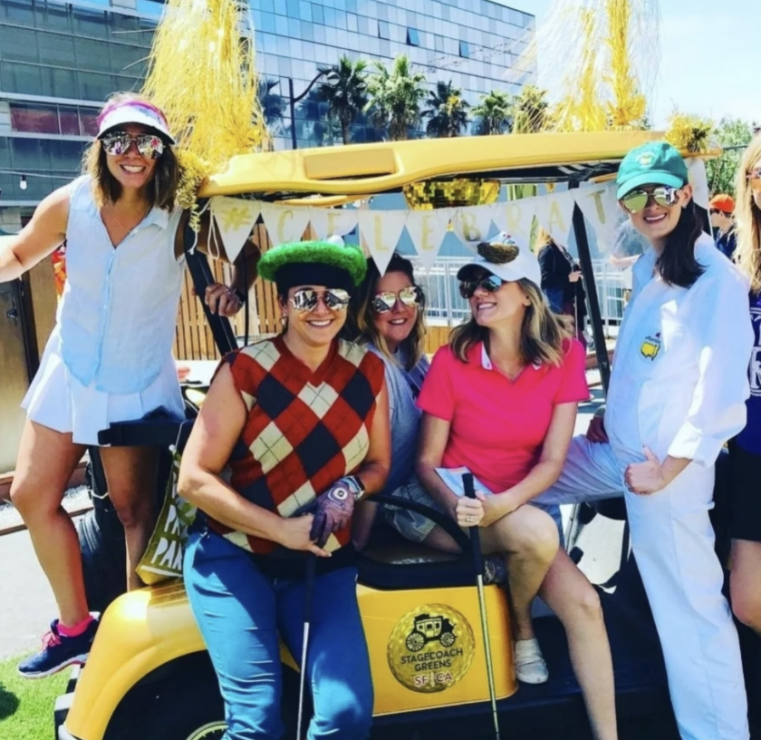 A team poses in front of a golf cart at Stage Coach Greens
